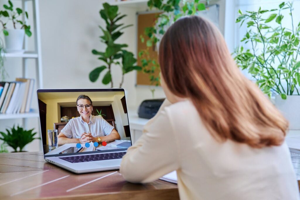 A student engaged in an online SAT tutoring session on her laptop with a professional Ostathi instructor