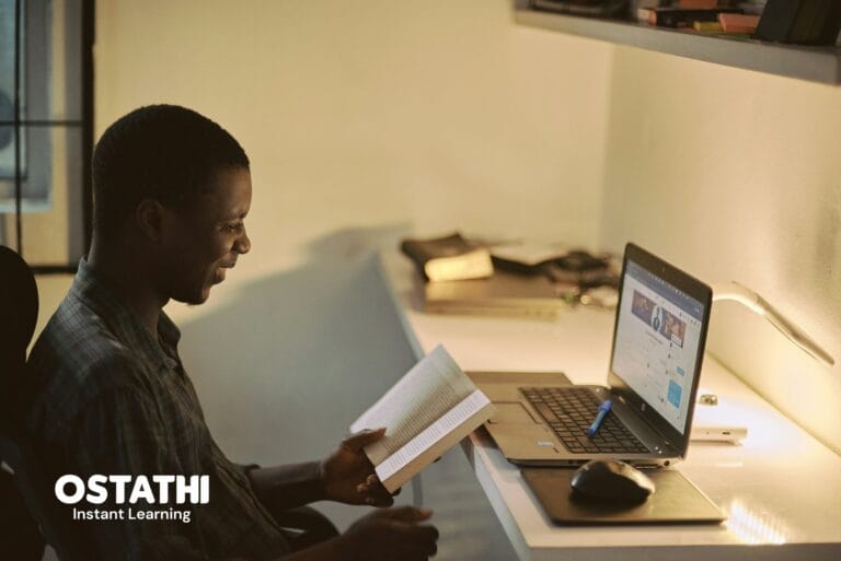 Student studying online using a laptop and book – online learning and distance education by Ostathi